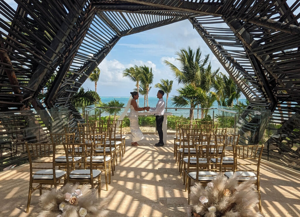 Bride and groom under wedding arch oceanfront in Mexico, one of the top locations for a destination wedding